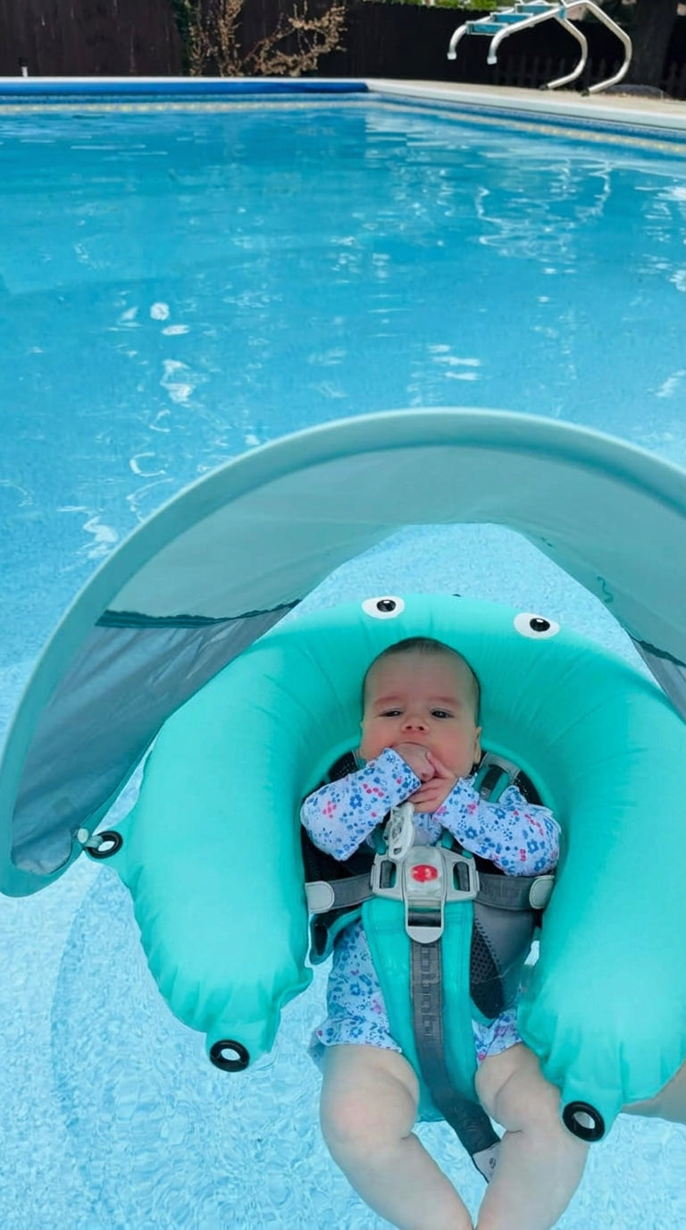 Baby shaded by the AquaNest sun canopy in a pool